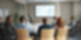 A man giving a presentation to a group of executive men and women in a conference room. On