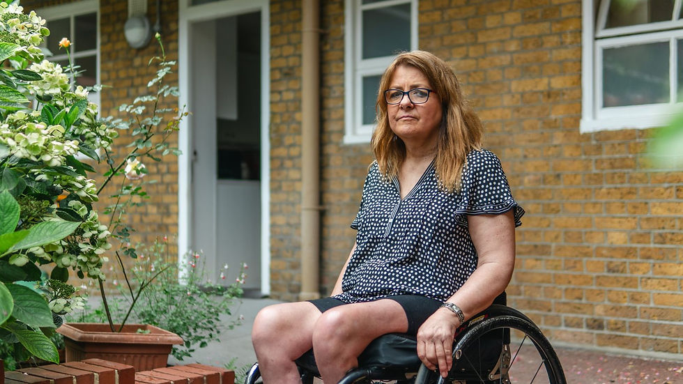 Woman using a wheelchair outside a brick building and garden