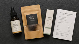 Comparatif CBD : sélection de produits sur ardoise anthracite — flacon, résine, e-liquide et document d'analyse, style éditorial