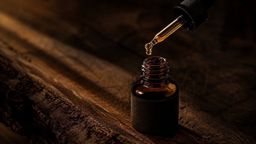 Flacon d'huile CBD full spectrum posé sur surface bois sombre, pipette avec goutte suspendue, lumière dorée rasante