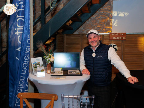Homme souriant à un stand avec ordinateur portable