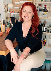 Femme rousse souriante dans son atelier d'artiste.