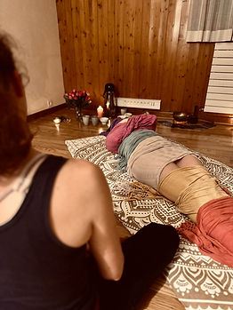Séance de relaxation avec une personne allongée sous des couvertures et des bougies.