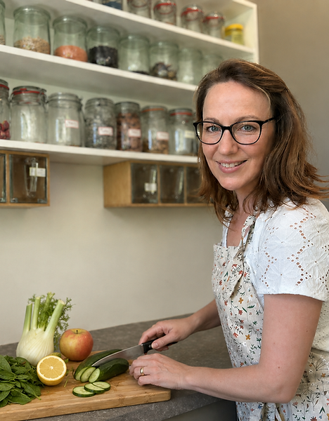 Femme souriante préparant des légumes pour un jus.
