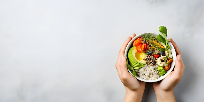 Mains tenant un bol de nourriture saine, avec avocat, légumes et herbes.