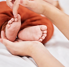 Mains adultes tenant et touchant délicatement les petits pieds d'un bébé.
