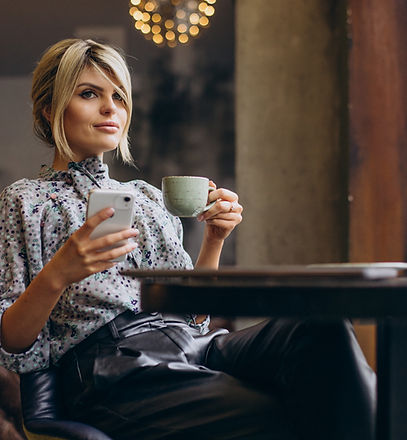 Femme élégante dans un café avec téléphone et tasse