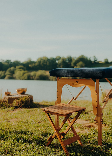 Table de massage en bois, tabouret, au bord de l'eau sereine.