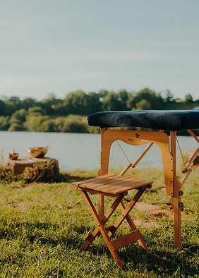 Table de massage portable et tabouret en bois près d'un lac tranquille.