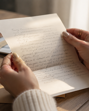 Mains tenant une lettre manuscrite sur une table en bois.