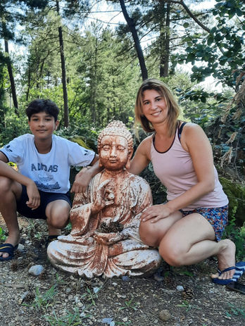 Femme et enfant posant près d'une statue de Bouddha en forêt.