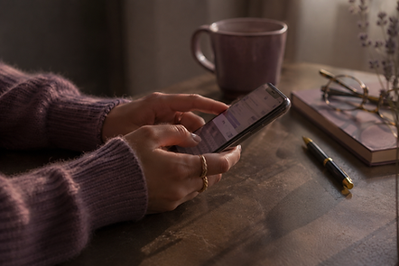 Mains utilisant un smartphone près d'une tasse de café.
