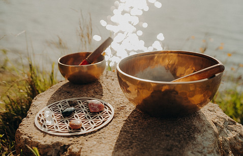 Deux bols chantants en bronze et cristaux près de l'eau scintillante.