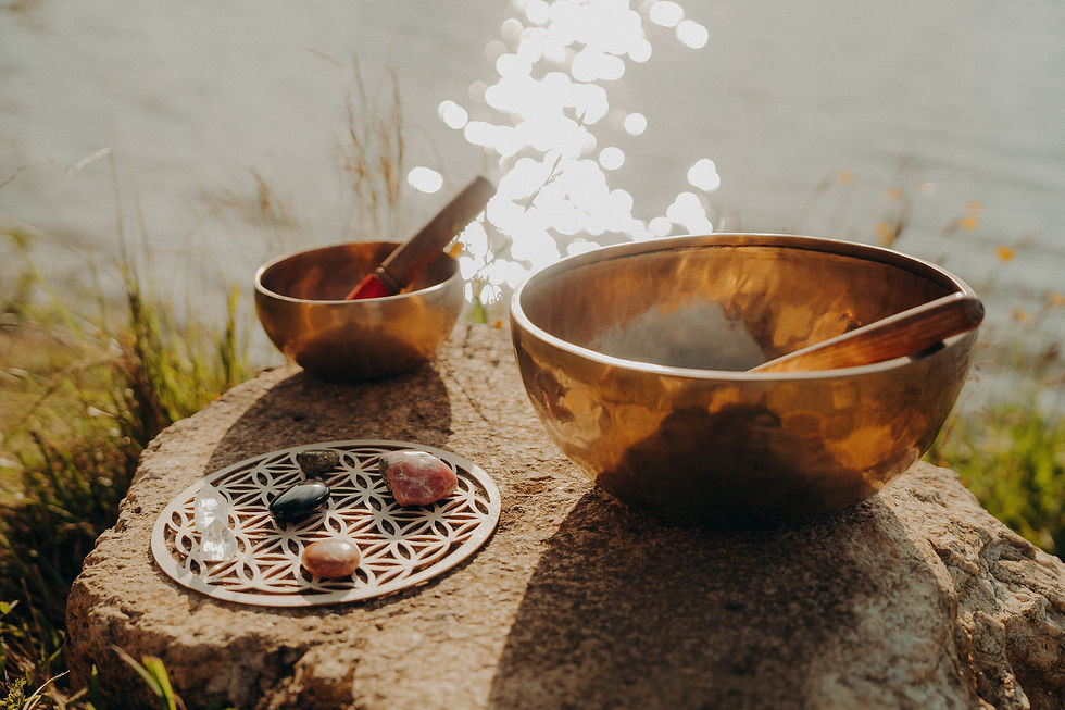 Deux bols chantants en bronze avec cristaux sur roche près de l'eau.