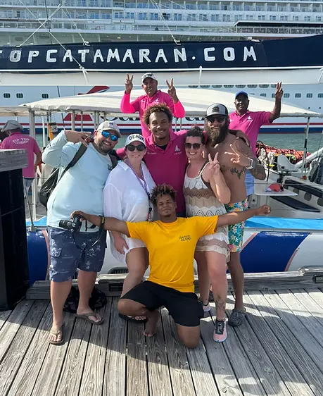 Group posing by a catamaran in Puerto Plata harbor.