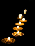 Bougies votives allumées en rangée diagonale dans l'obscurité profonde.