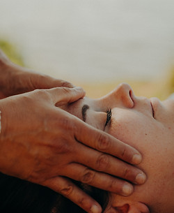 Mains expertes massant délicatement le visage d'une personne pendant un soin relaxant.