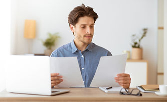 Homme examinant des documents devant son ordinateur au bureau