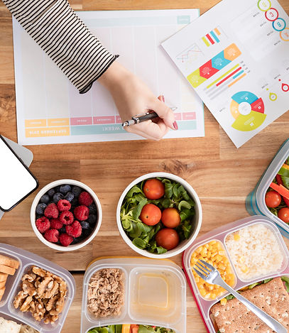 Personne organisant des repas sains sur un bureau avec ordinateur.