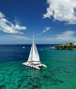 White catamaran sailing in clear turquoise tropical water