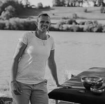 Femme souriante appuyée sur une table de massage extérieur près de l'eau.