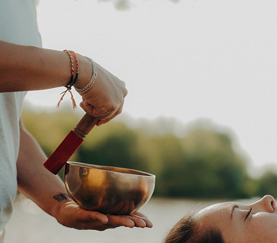 Thérapeute utilisant un bol chantant pour thérapie sonore relaxante en extérieur.