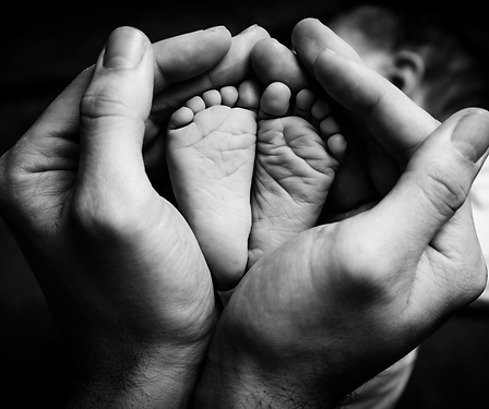 Mains d'adulte tenant tendrement les petits pieds d'un bébé nouveau-né.