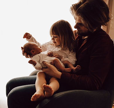 Un père qui porte sur ses genoux sa fille et son nouveau né