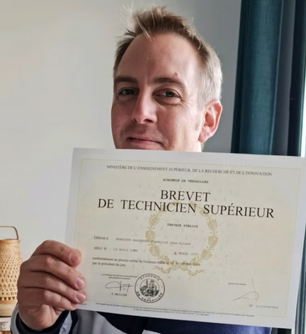 Homme souriant tenant son Brevet de Technicien Supérieur