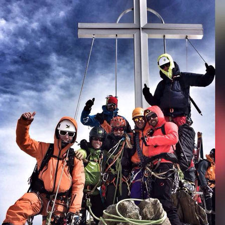 Image de plusieurs skieurs qui prennent la pose devant une croix