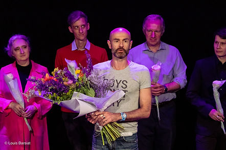 Trois hommes sur scène recevant des fleurs après un spectacle.