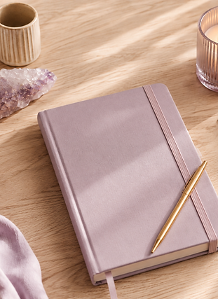 Carnet lilas avec stylo doré, bougie et cartes de tarot.