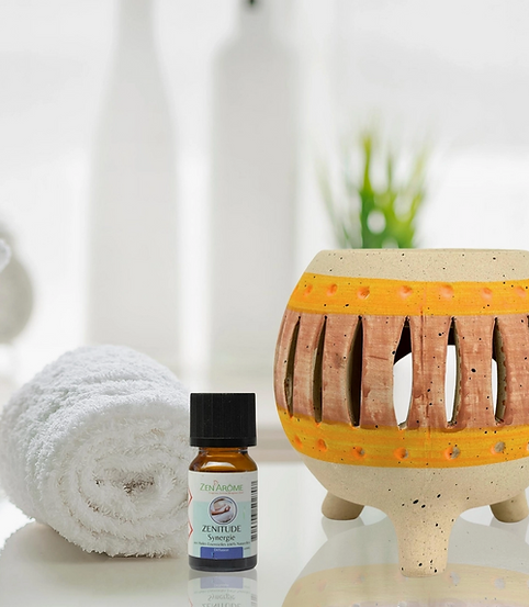 Diffuseur d'huile essentielle avec flacon, serviette roulée et fond blanc pour détente.