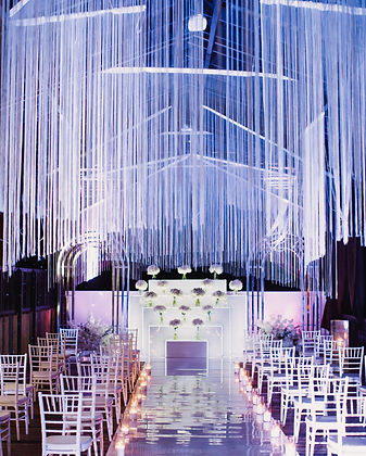Salle de cérémonie avec chaises blanches et rubans lumineux.