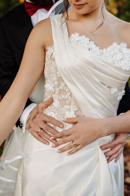 Mariée en robe blanche avec dentelle, homme tient ses mains sur elle.