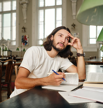 jeune-etudiant-masculin-attrayant-avec-des-livres-revant-pendant-ses-etudes-a-la-bibliothe