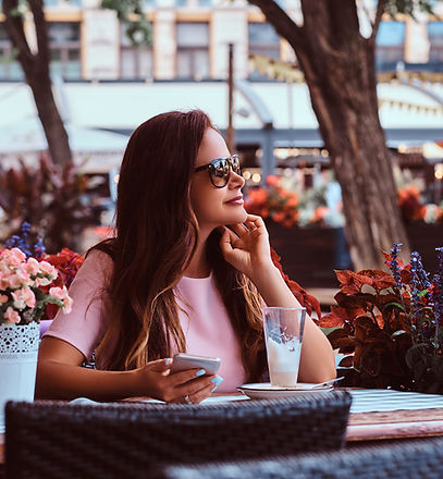 Femme en lunettes de soleil attablée à un café en terrasse avec un sac seconde main Dior