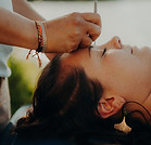Femme recevant un soin du visage avec outil en pierre, extérieur.