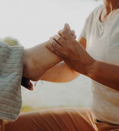 Une personne masse doucement le pied d'une autre en extérieur.