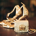 Chaussures à talons dorées, pochette scintillante, bijoux