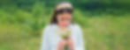 Jeune femme sentant des fleurs sauvages dans un champ vert.