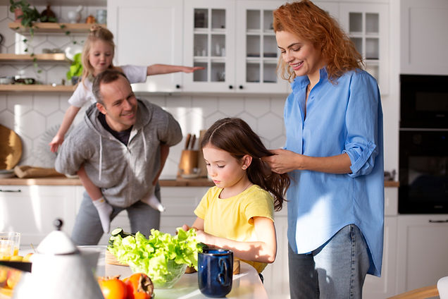 Famille heureuse cuisine ensemble. Mère coiffe sa fille, le père et sa fille jouent.