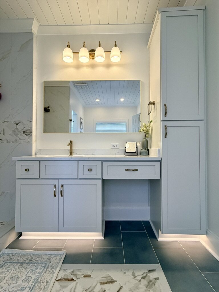 Bathroom vanity with brass fixtures and a gold-framed mirror
