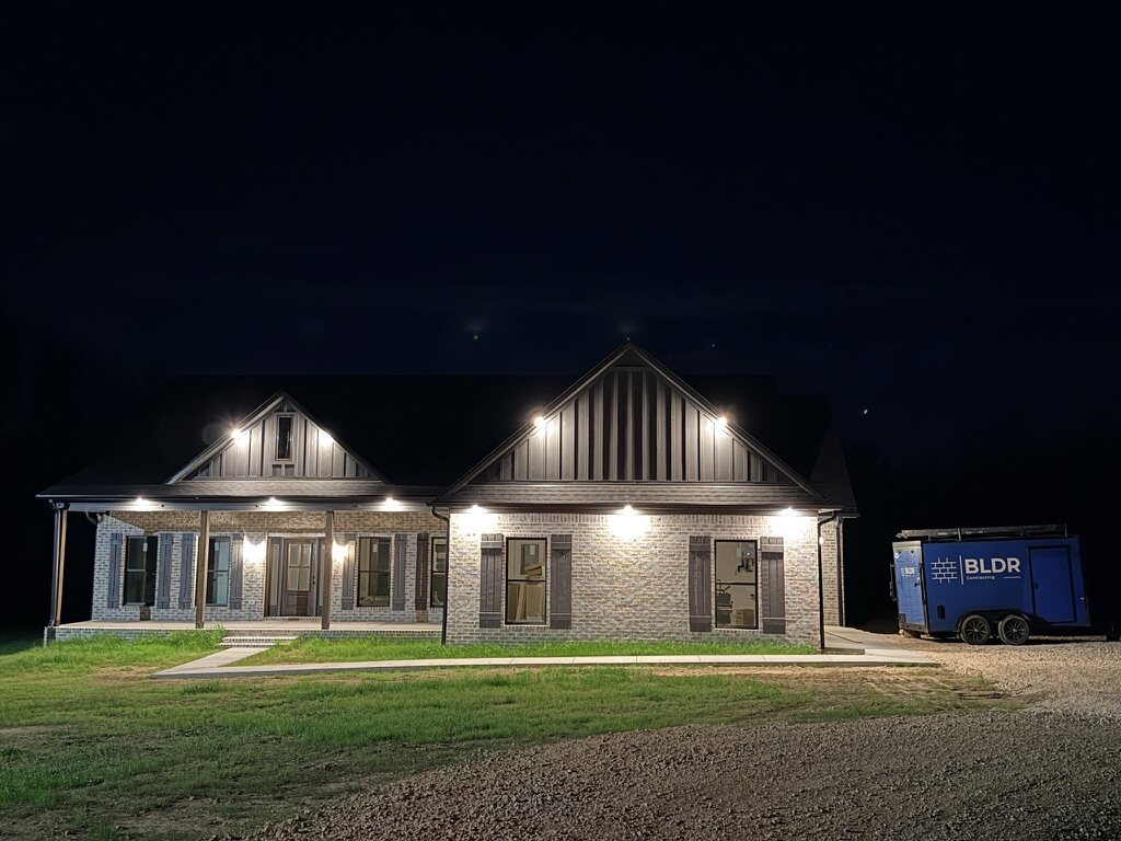 A BLDR-built brick home with a deep front porch, lit at dusk