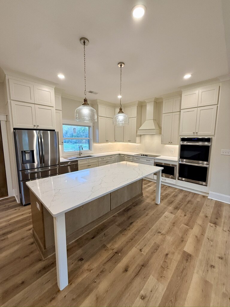 Kitchen with a quartz-topped island, double wall ovens and a custom range hood
