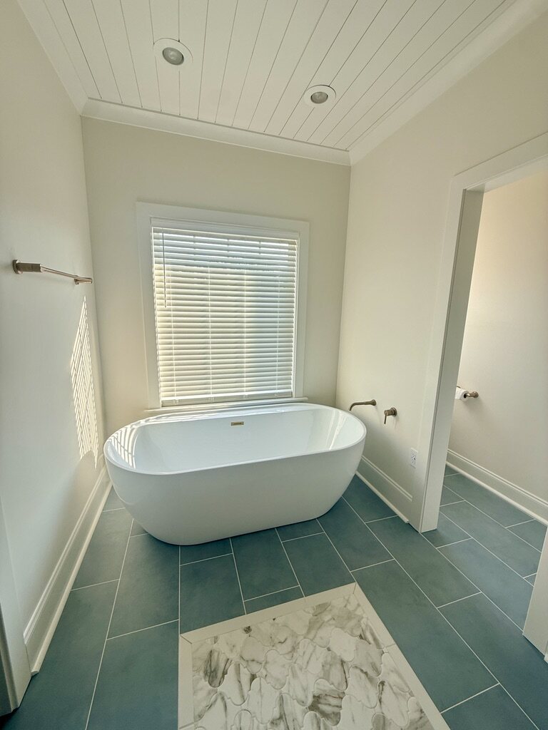 Freestanding soaking tub on slate-look tile with a marble inlay
