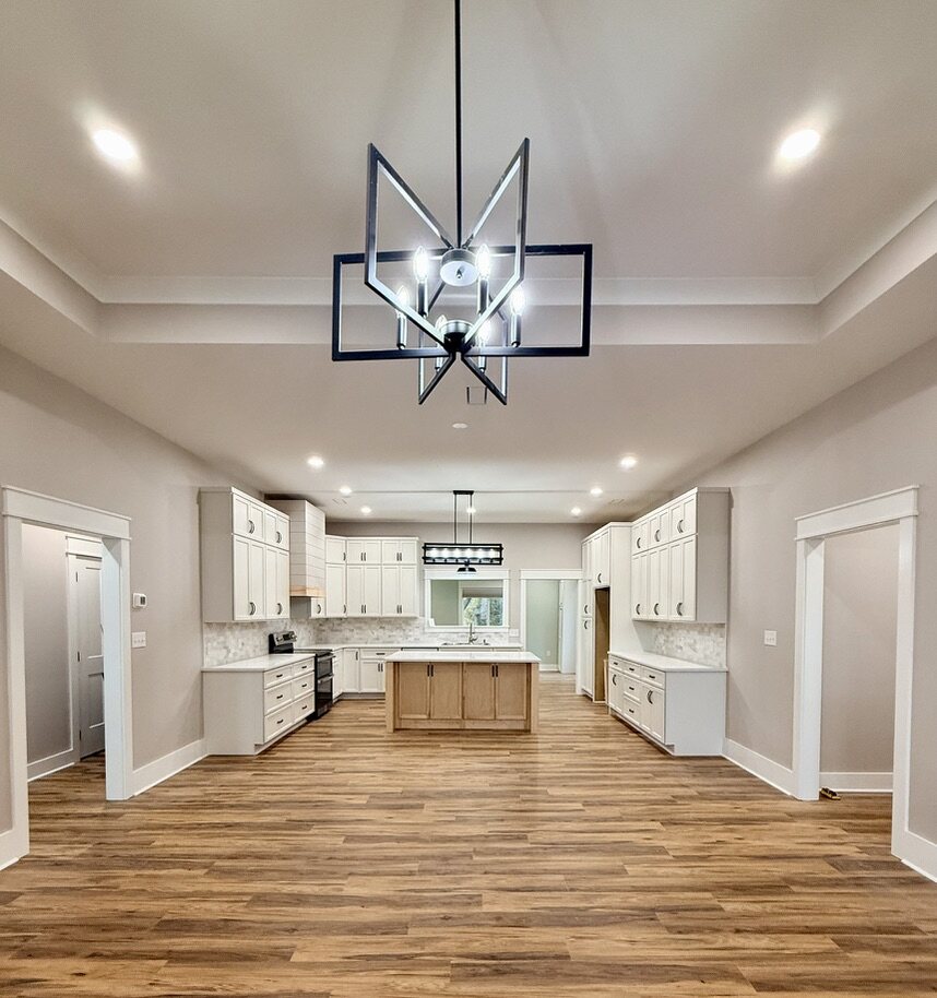 Open kitchen with a black geometric chandelier and white cabinetry