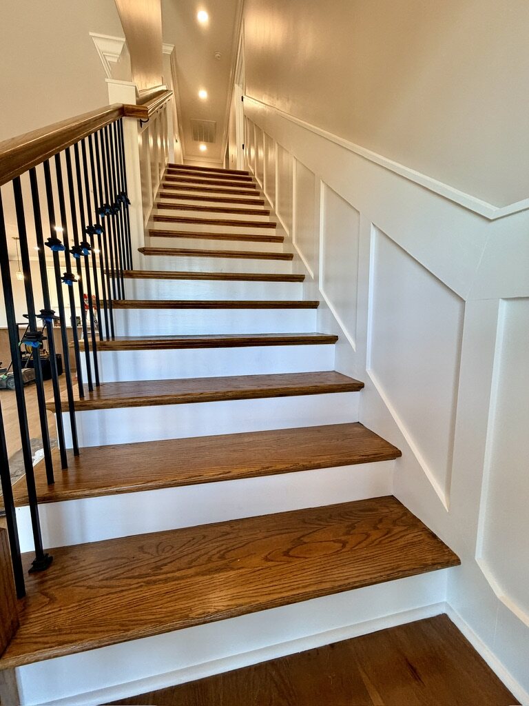 Staircase with oak treads, iron balusters and paneled wainscoting