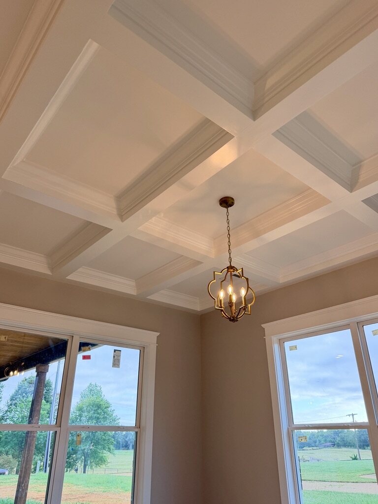 Coffered ceiling with layered crown molding and a brass pendant