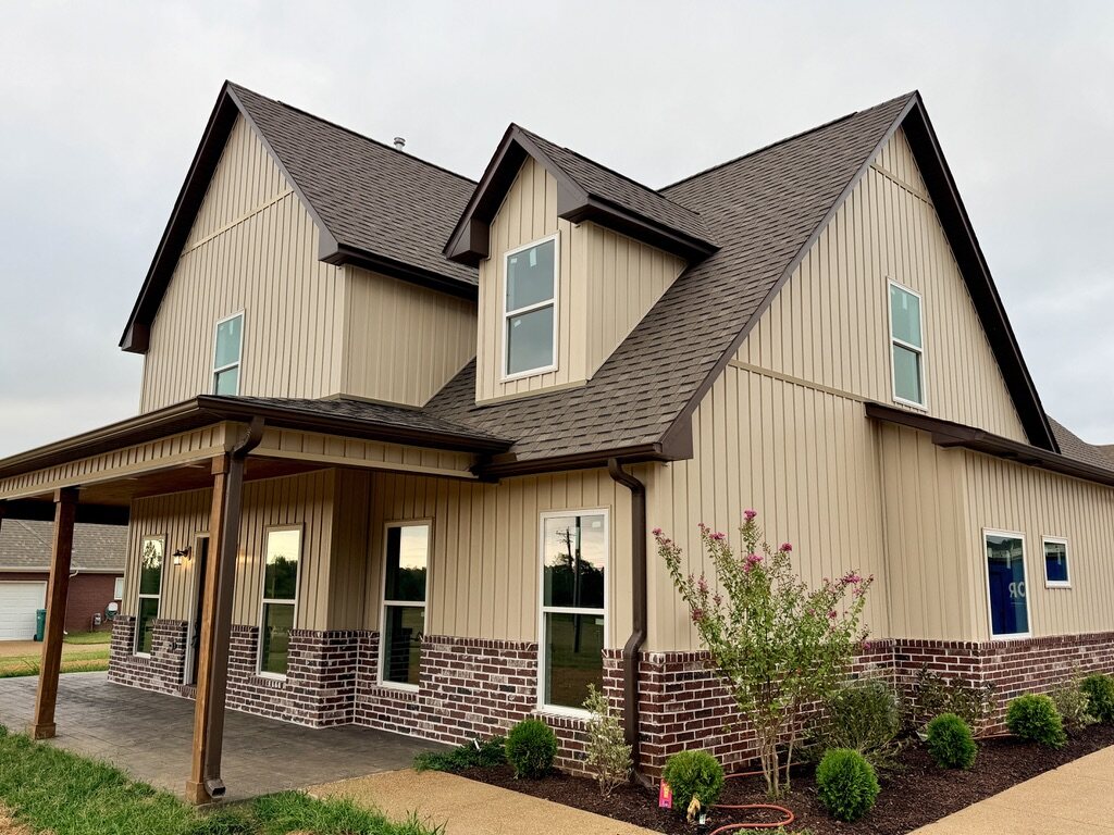 Two-story home with vertical siding, dormers and a brick base